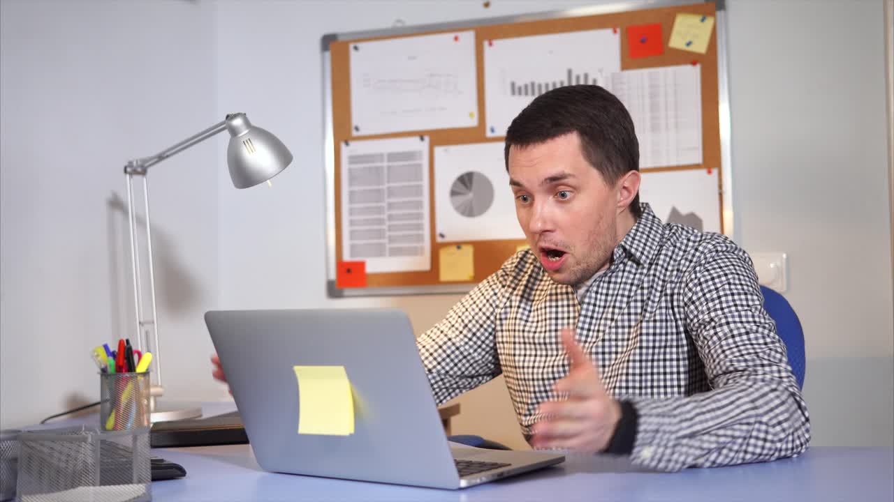 hombre sorprendido por una computadora portátil en el escritorio de la oficina