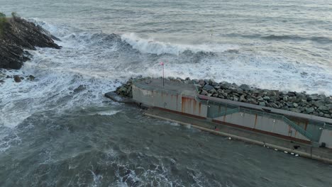 sea waves entering genoa harbor through narrow pass dammed by pier