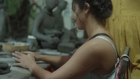 woman sculpting clay figure at a pottery workshop, focused and engaged in her craft
