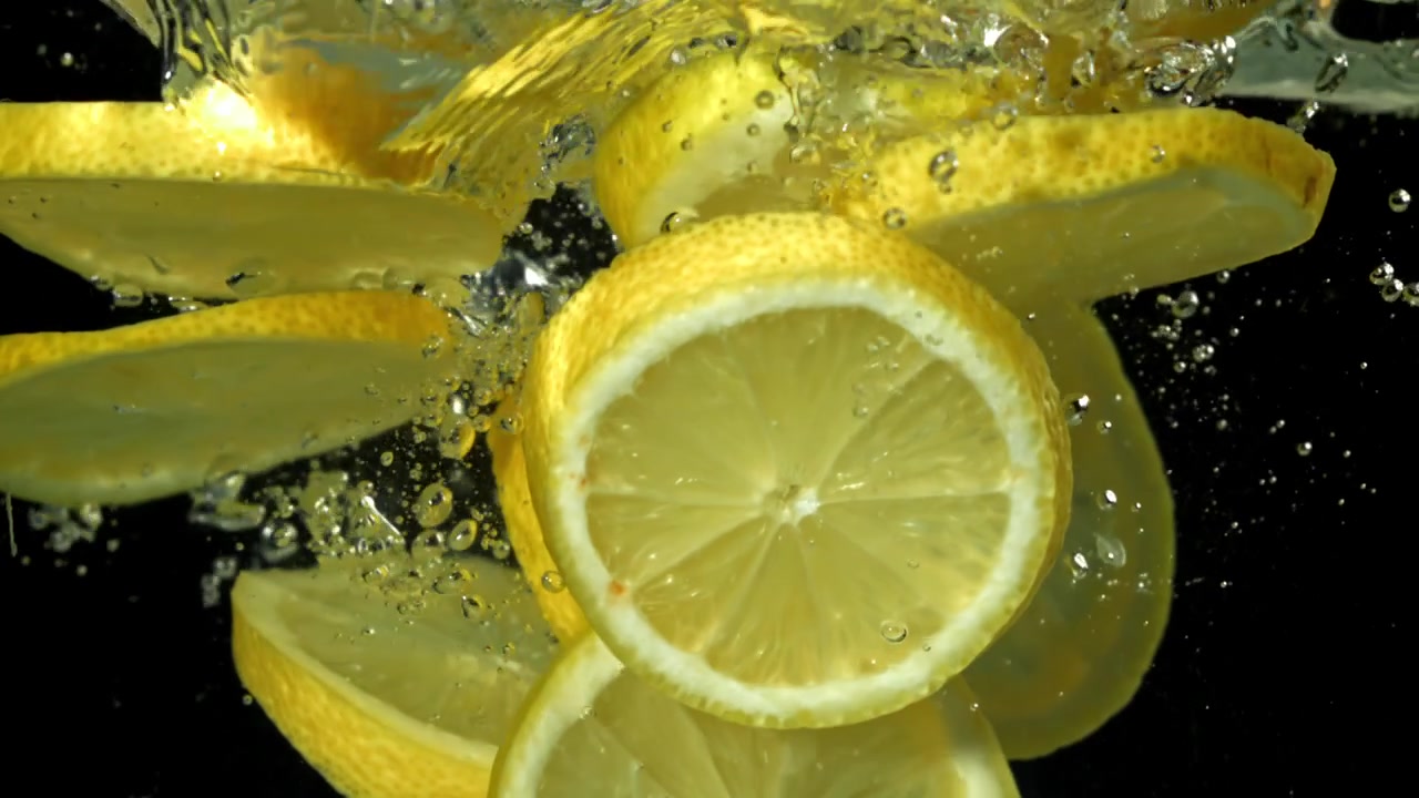 Rallentatore di fette di limone fresche che cadono nell'acqua