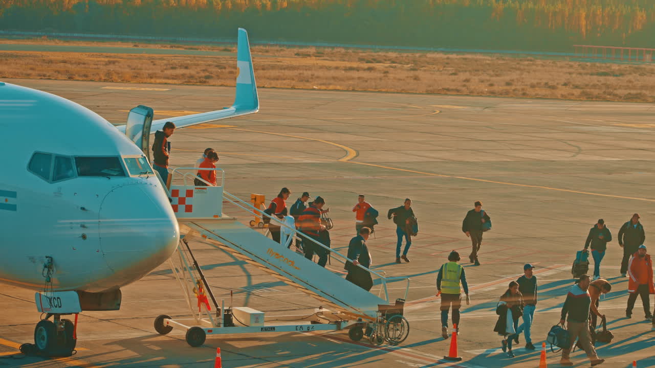 Passengers Disembarking an Airplane on the Tarmac at Sunset