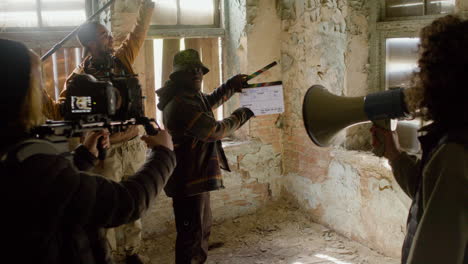 Production-team-and-cameraman-recording-the-scene-of-a-girl-trying-to-escape-through-the-window-of-a-ruined-building