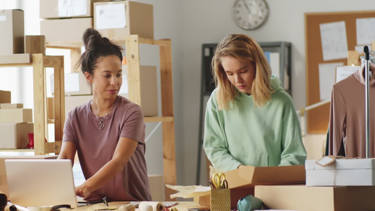 Women Packing Parcels and Working on Laptop in Office