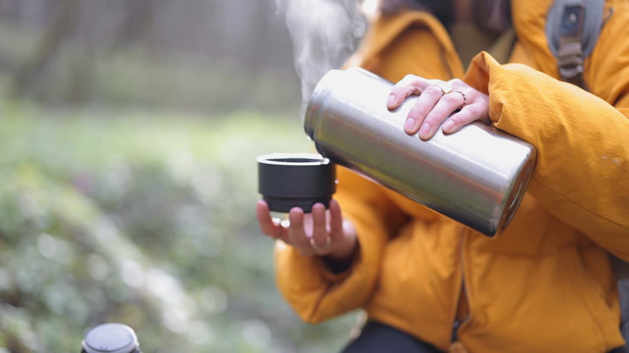 여자 는 숲 에서 테르모스 에서 뜨거운 차 를 마신다