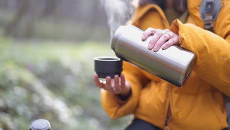 woman drink hot tea from thermos in forest