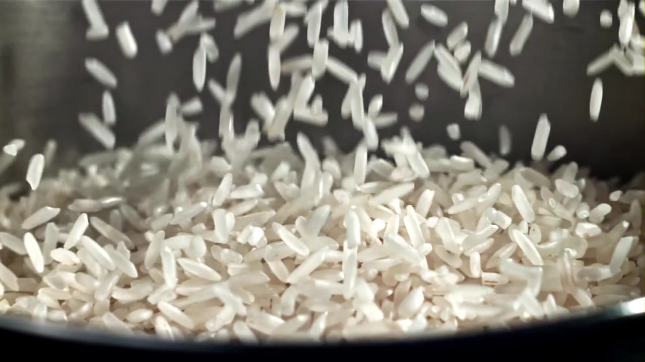 Chicchi di riso bianco che cadono in una pentola al rallentatore