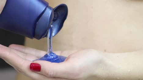 pouring blue shampoo or liquid soap into hand