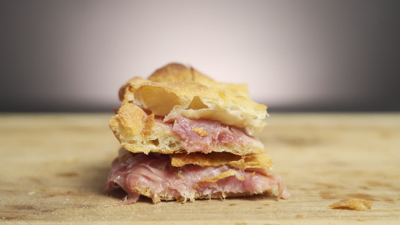 영화 장면에서 나무 보드에 모짜렐라와 프로슈토로 가득 찬 피자 알 탈리오 한 조각을 손에 들고