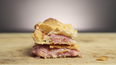 manos tomando un trozo de pizza al taglio relleno de mozzarella y prosciutto en una tabla de madera en una escena cinematográfica