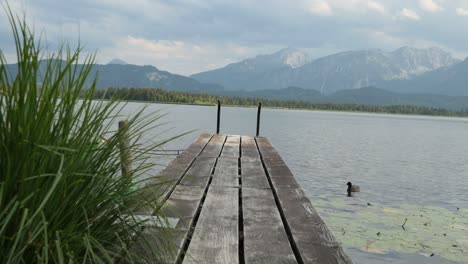 Embarcadero-De-Madera-En-El-Lago-Hopfensee-Cerca-De-Fuessen-Con-Montañas-En-El-Fondo,-Baviera,-Alemania