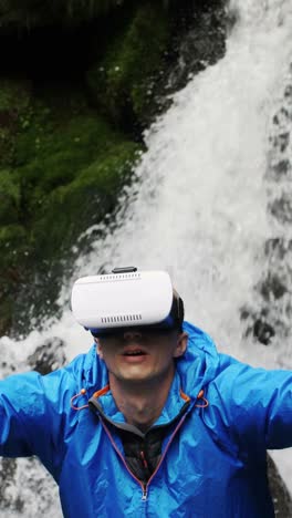man wearing vr headset by a waterfall