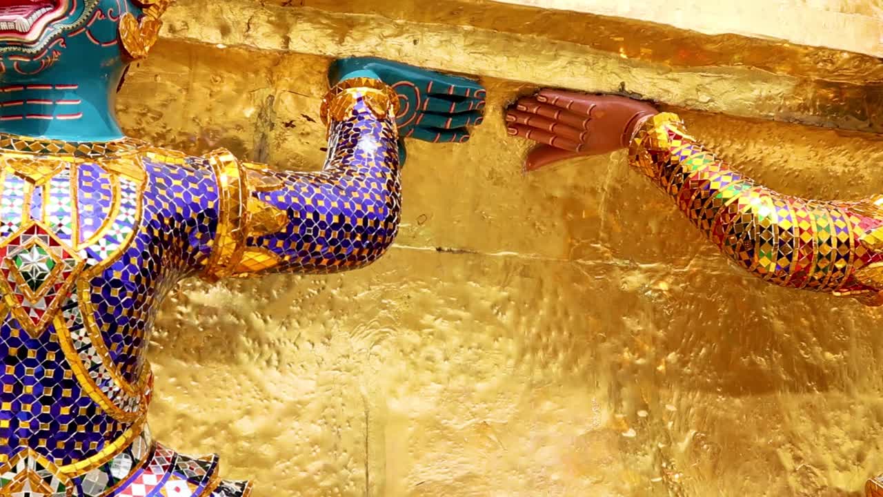 Close-up of colorful guardian statues adorned with intricate mosaics against a golden backdrop.