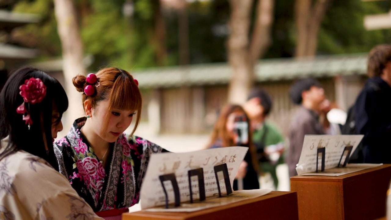 一名身穿傳統和服的年輕日本女子在東京神社閱讀籤文。