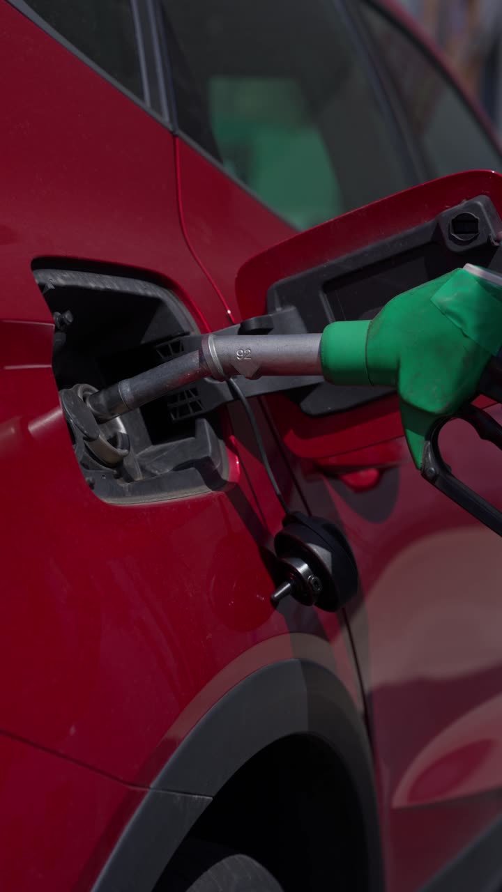 Hand Pumping Gas into Red Car at Fuel Station