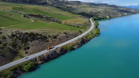 Drone-around-road-that-runs-along-blue-new-zealand-lake