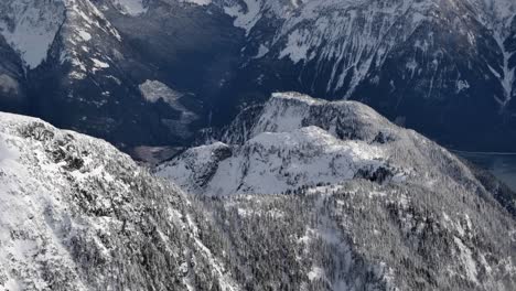 Vista-Aérea-De-La-Cima-De-La-Montaña-Cubierta-De-Nieve-En-Un-Día-Soleado