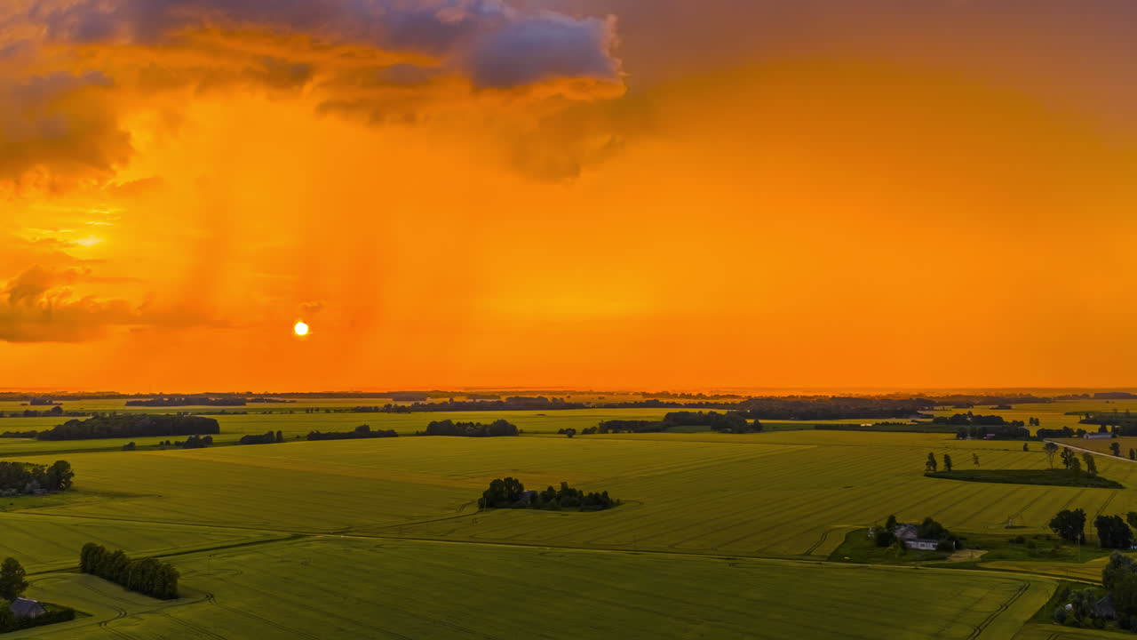 Magnificent glowing orange golden sunset cloudscape over farmland fields of grain crops - high altitude aerial time lapse