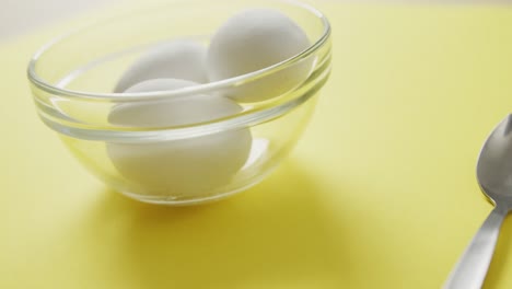 video of close up of glass bowl with eggs on yellow background