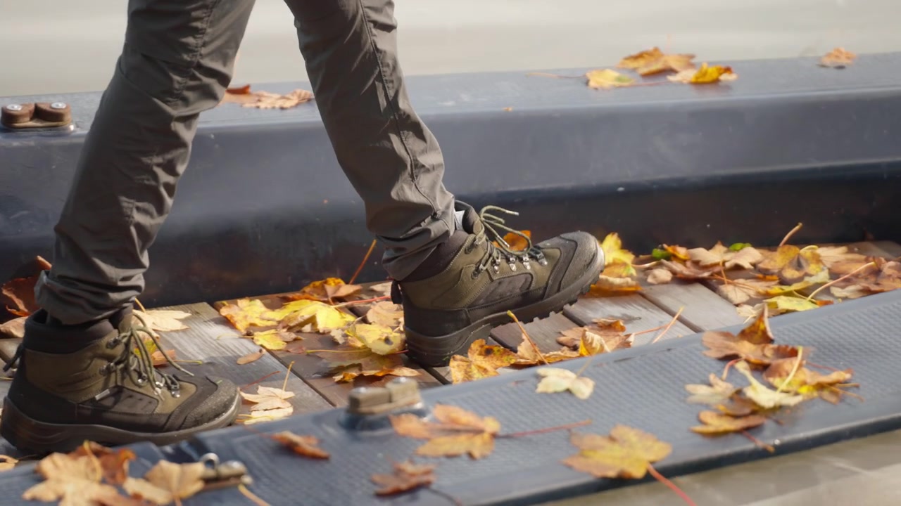 En person balanserer i en båt, navigerer gjennom spredte høstblader mens han nyter en fredelig ettermiddag på et rolig vann omgitt av natur