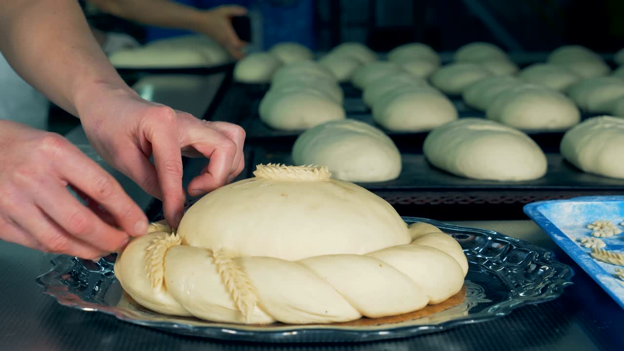 베이커는 반죽 조각으로 둥근 을 장식하고 있습니다.