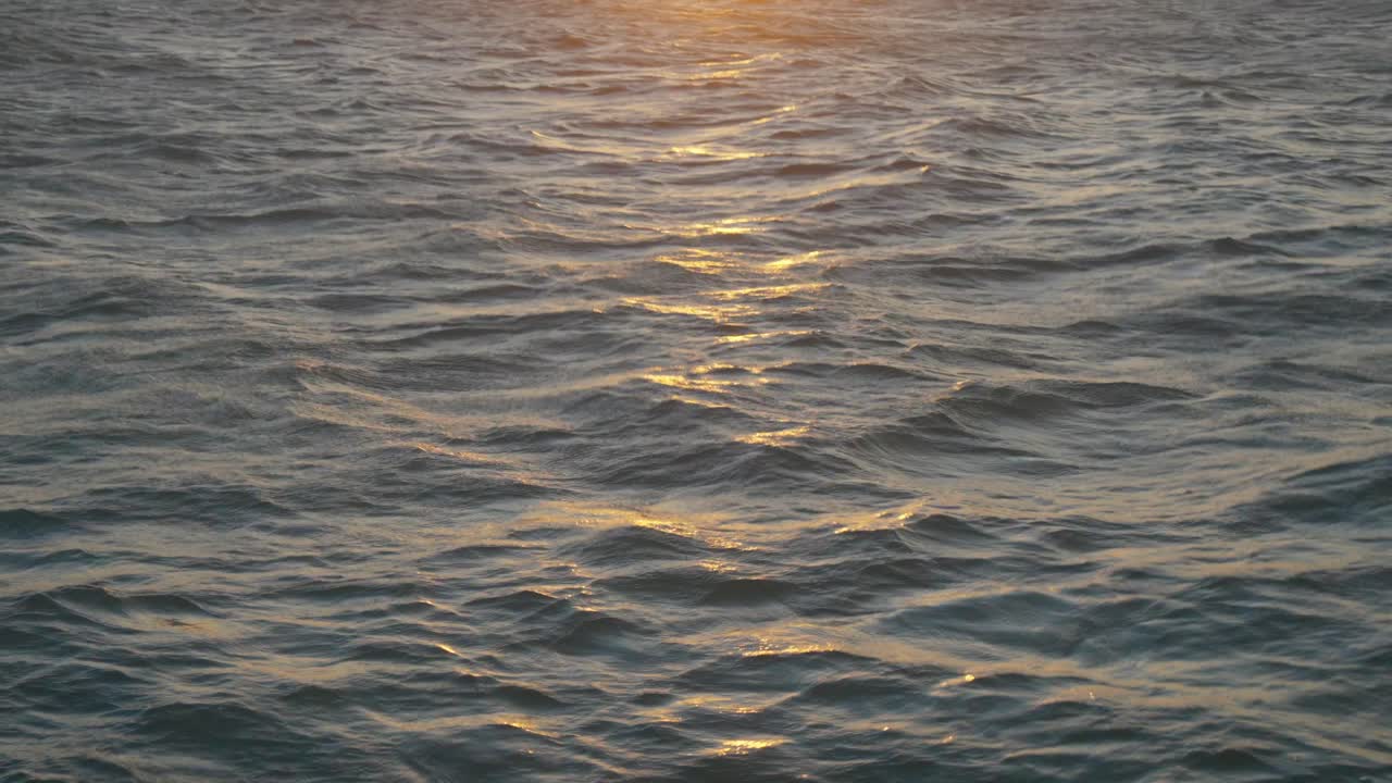 Beautiful scene starting with the gentle waves of the sea, revealing a magnificent orange sunset