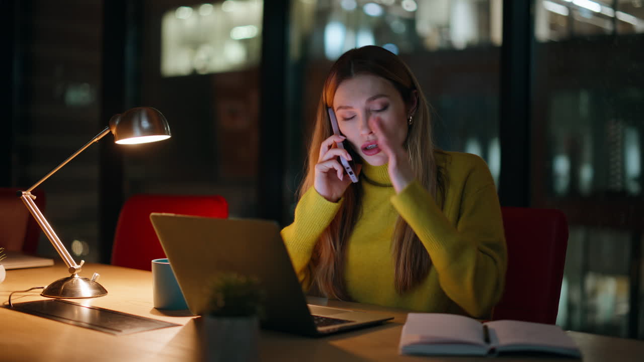 Entreprenør ringer sent om aftenen på kontoret, siddende ved bærbar computer, arbejdsplads tæt på