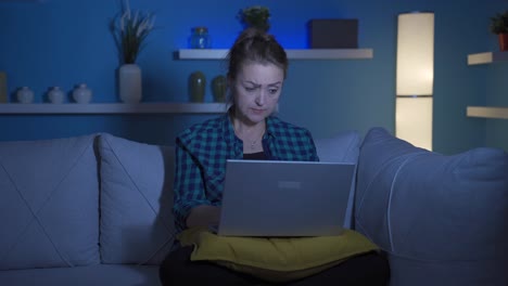 Woman-focusing-on-computer-has-serious-expression.-At-home-at-night.