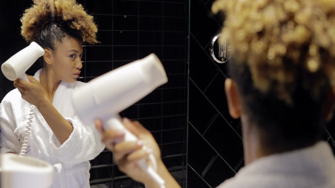 Charming girl in bathroom using hairdryer