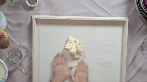 top down overview of chef kneading handmade busiate pasta dough ball on prep surface