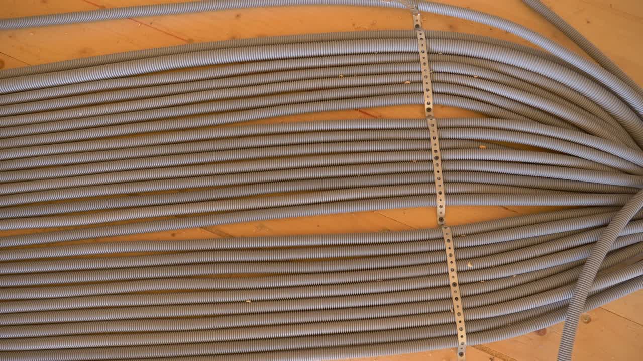 TOP DOWN: Grey corrugated tubing runs along the wooden floor of unfinished house