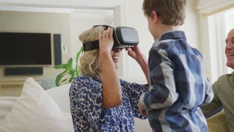 happy senior caucasian couple with grandson using vr headset in living room