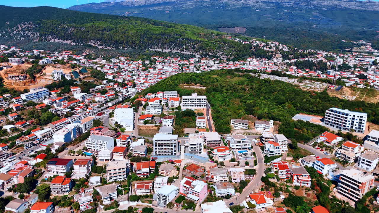 Red-roofed urban landscape located on the beautiful green mountains. Montenegro scenery from aerial perspective
