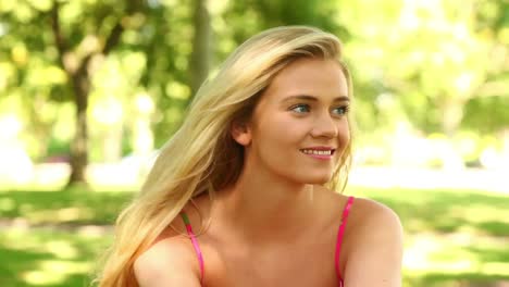 Pretty-blonde-relaxing-in-the-park-and-smiling-at-the-camera