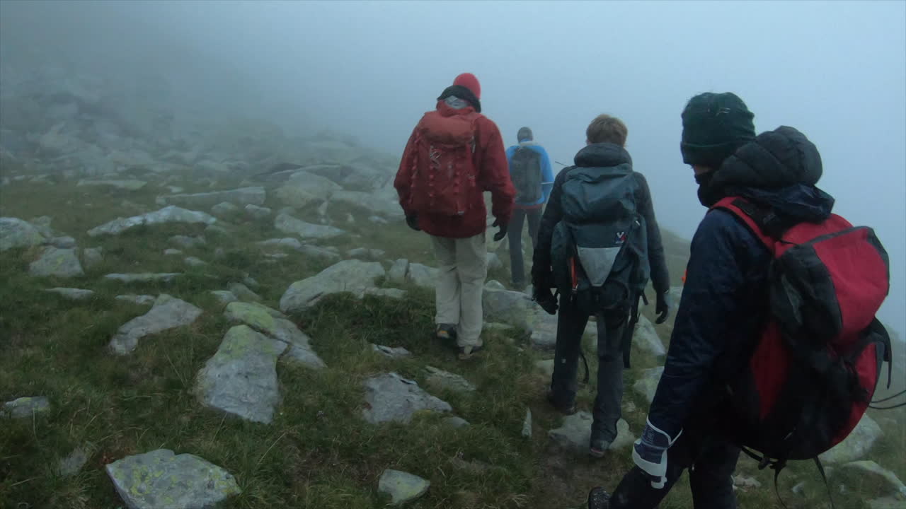 camine por la mañana, los alpinistas están equipados con mochilas, chalecos y atraviesan la niebla en un pequeño camino de grava, suiza