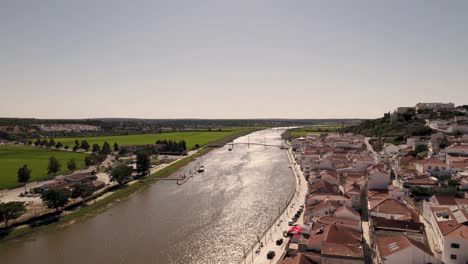 aerial dolly in overlooking at sado river, riverside parish townscape and agriculture lands