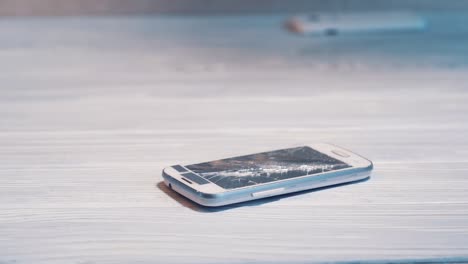 mobile phone is falling on the ground and splits into parts, man's hand taking it off. sensory phone falls on the wooden floor and destroys.