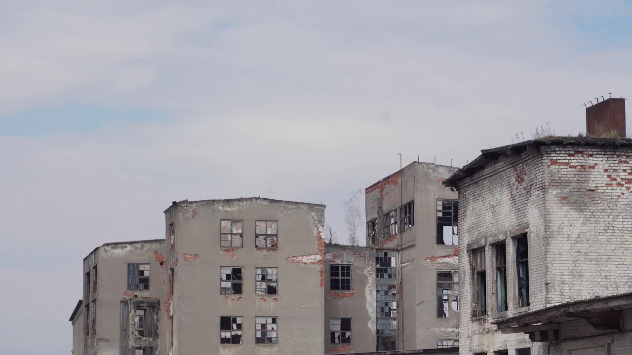 Broken high-rise buildings. The ruins of the factory, houses. Broken windows in houses. Roofs with moss and plants
