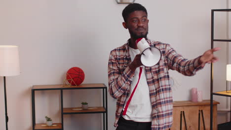 Young-man-shout-in-megaphone-loudspeaker-announces-discounts-sale-of-real-estate-at-home-on-sofa