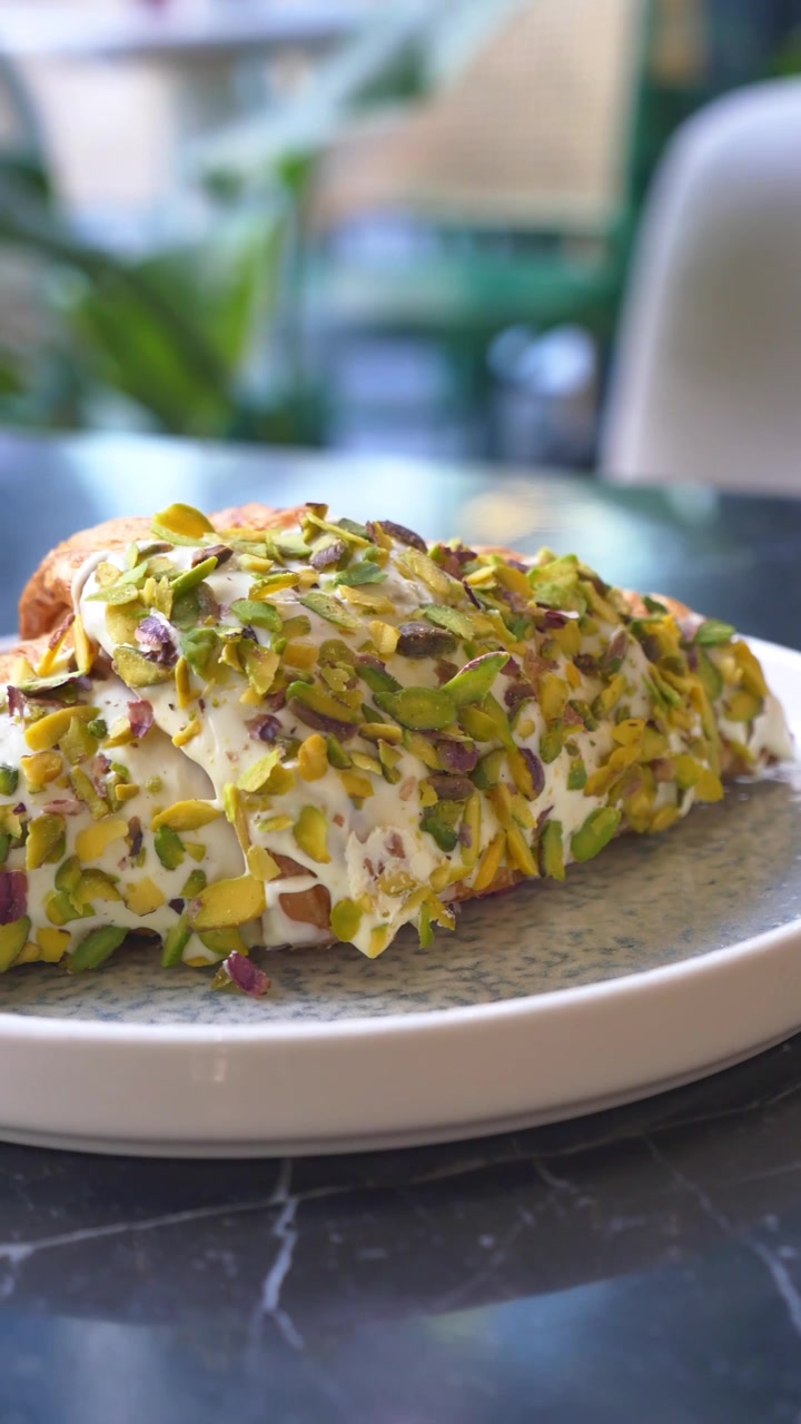Croissant ricoperto di pistacchio su un piatto in una caffetteria