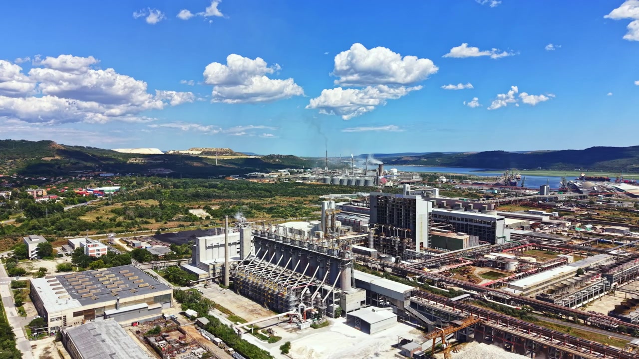 Área industrial com fábricas e nuvens no céu perto de um corpo d'água durante o dia