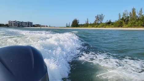 motor boat driving boat wake waves from outboard engine in florida backwater mangroves along tropical seashore beach