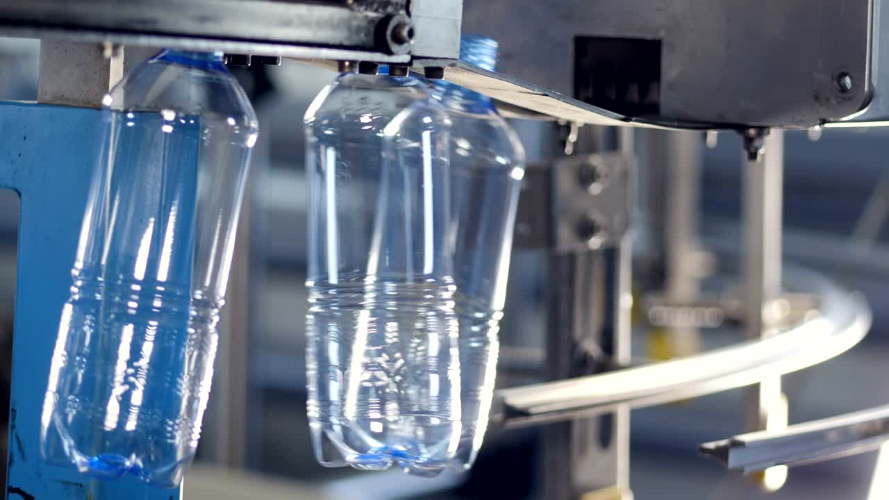 botellas de mascotas claras de tamaño medio que se mueven rápidamente en rieles de guía.