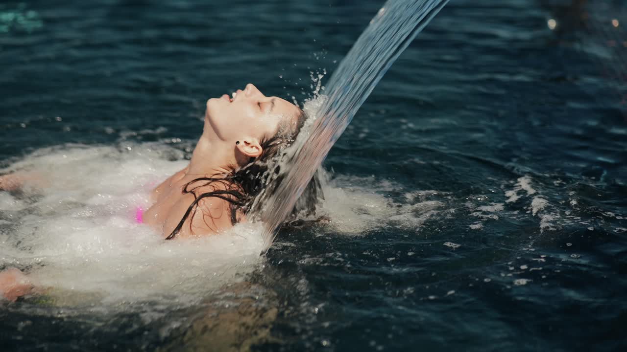 Donna che si gode un gioco d'acqua in piscina