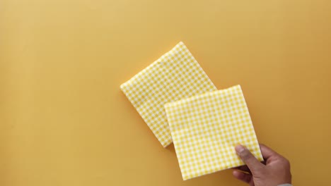 a man's hand holding a folded yellow and white checkered napkin