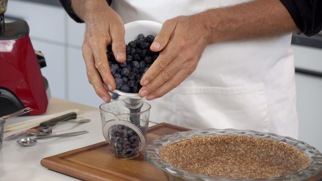 Tilføjelse af blåbær til kop for at lave hjemmelavet mælkefri vegansk plantebaseret cheesecake til sund spisning