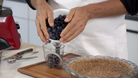 Adding-blueberries-to-cup-to-make-homemade-dairy-free-vegan-plant-based-cheesecake-diet-healthy-eating