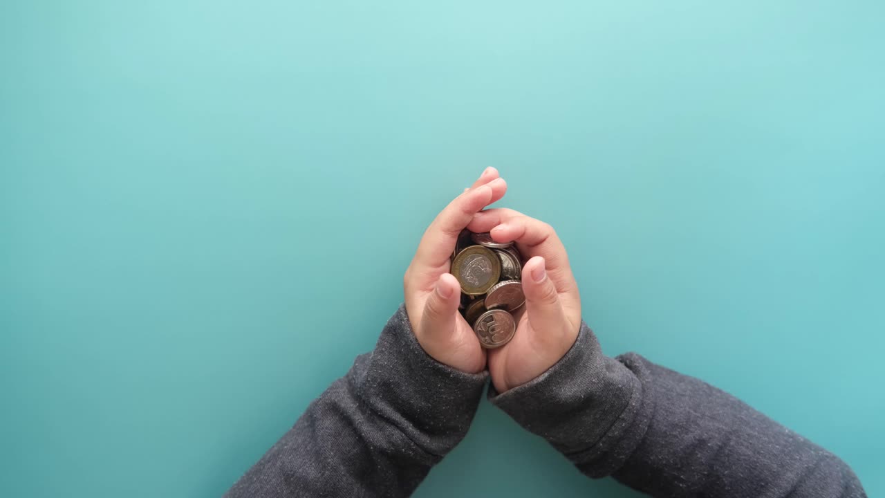 las manos del niño sosteniendo monedas de euro