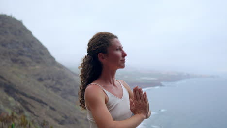 amidst the scenic beauty of the blue ocean at sunset, a young woman does yoga on a rocky seashore, representing a healthy lifestyle, harmony, and the symbiotic relationship between humans and nature