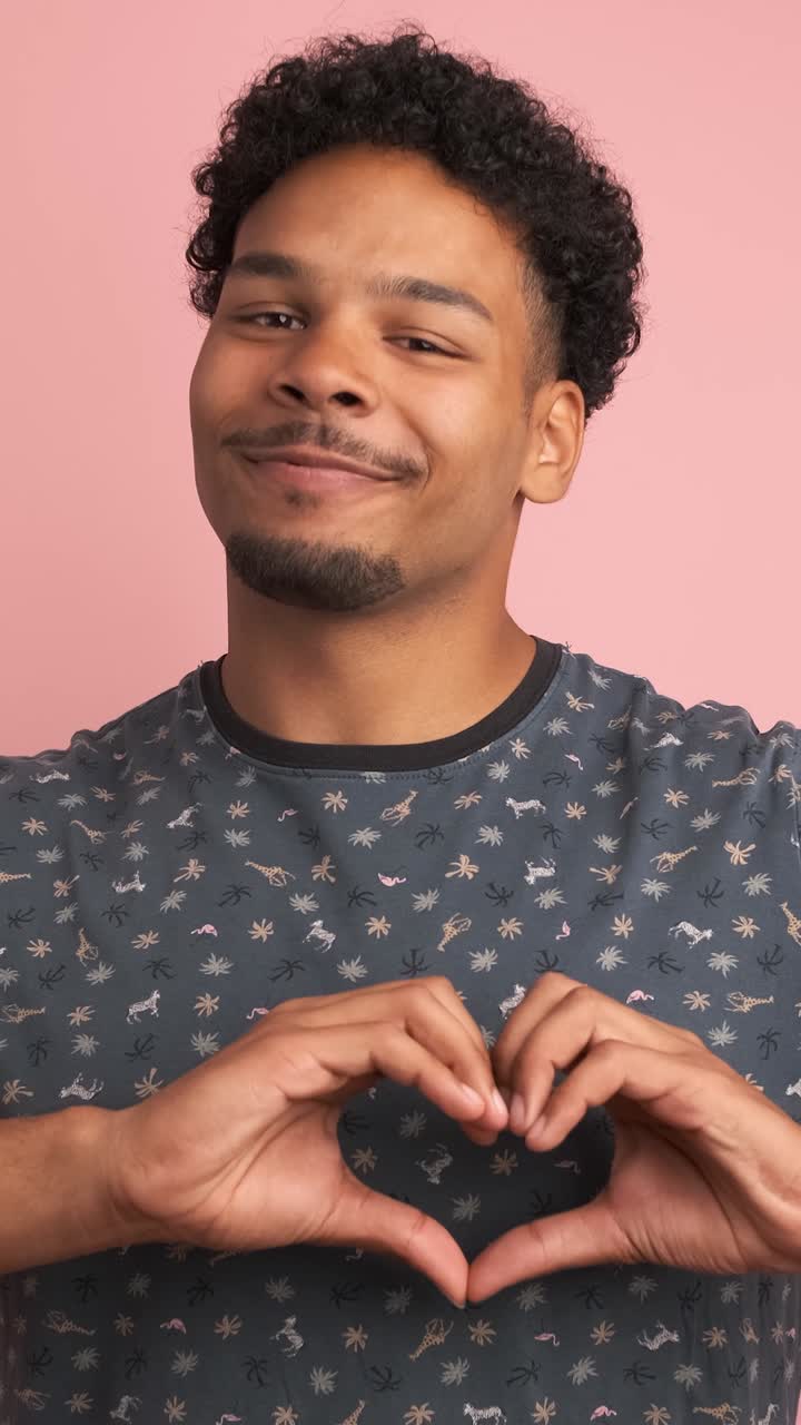 Happy young man gesturing heart with fingers