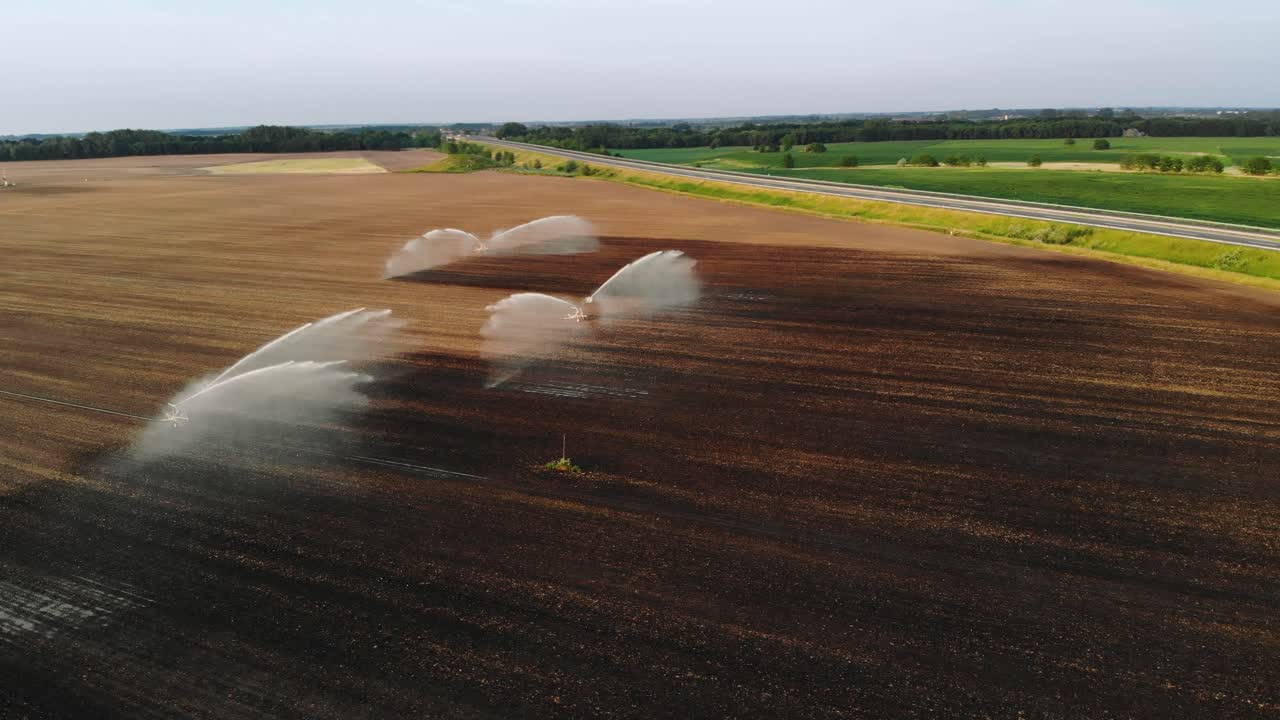 Watering dry land next to a highway with sprinklers, drone shot panorama